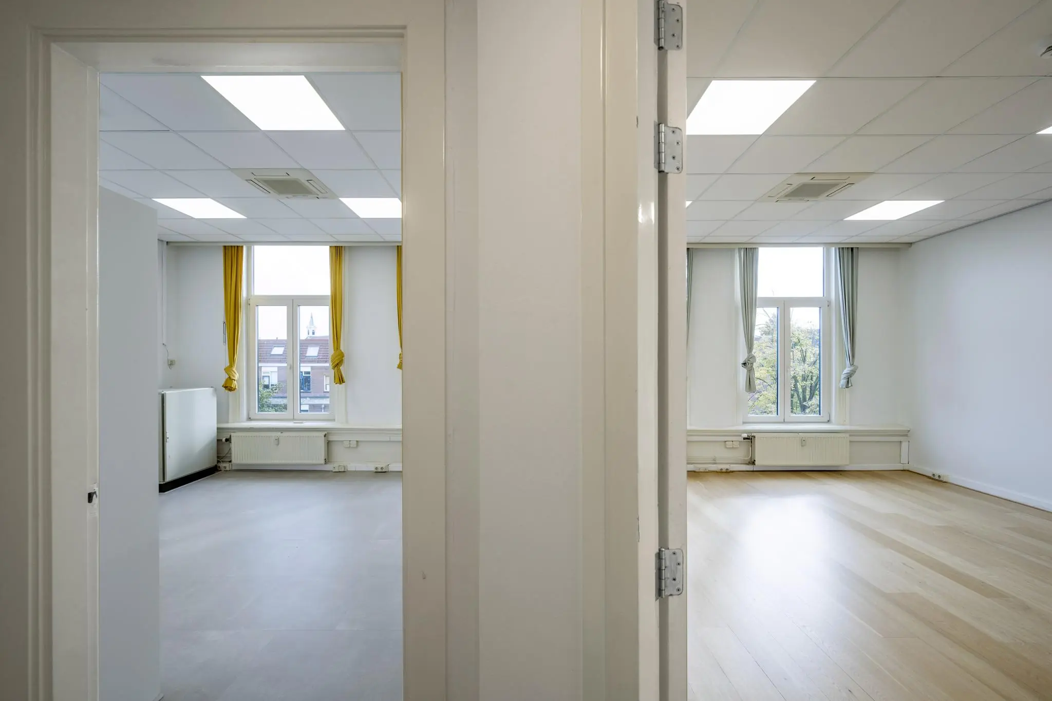 Twee aangrenzende, lichte kamers met grote ramen en verschillende vloerafwerkingen in een pand aan de Nieuwe Gracht.